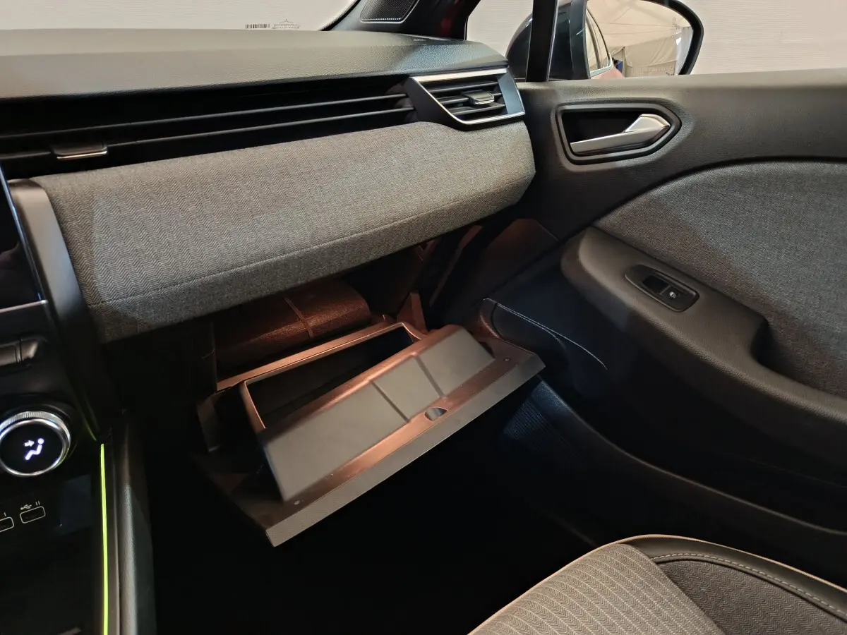 Intérieur côté passager de la Renault Clio Techno TCe 90 2024, boîte à gants ouverte et tissu gris texturé sur la planche de bord.