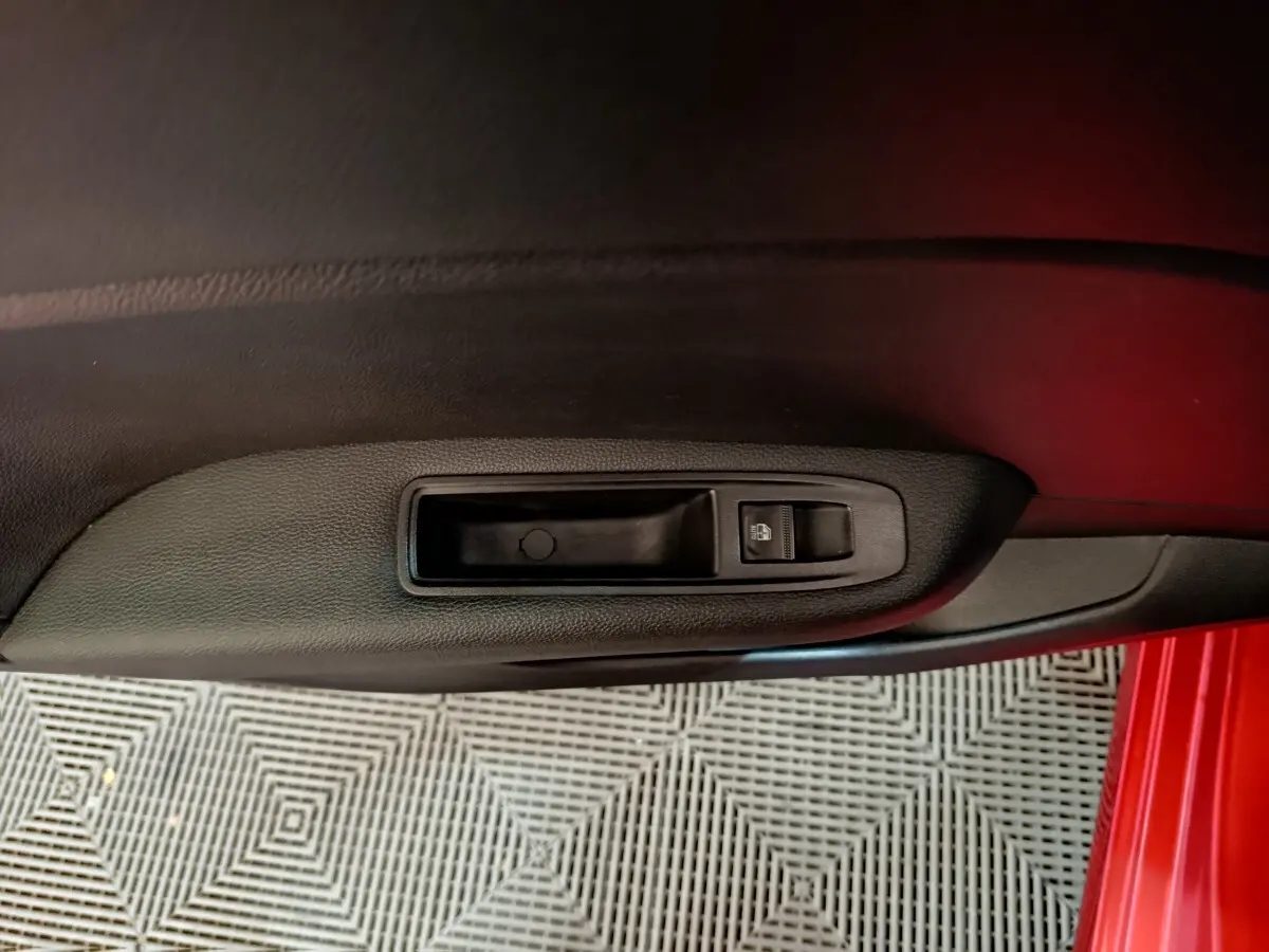 Gros plan sur la commande de lève-vitre côté conducteur de la Renault Clio Techno TCe 90 rouge 2024.