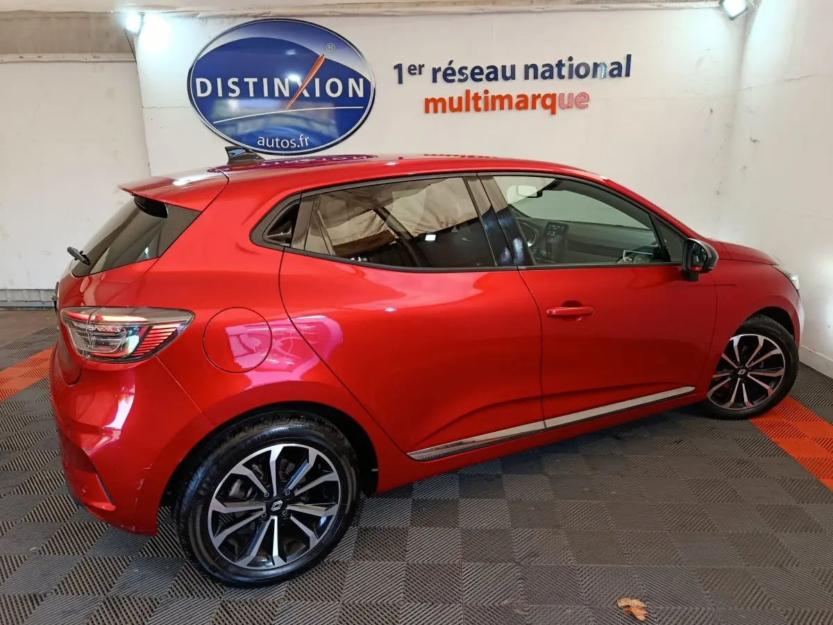 Renault Clio Techno TCe 90 rouge vue de profil côté gauche, avec jantes alliage et vitres teintées.