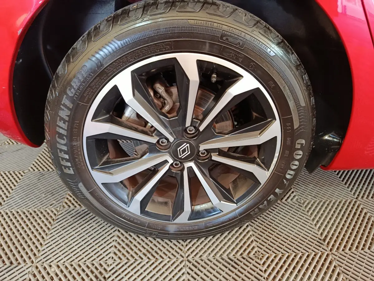 Gros plan sur la roue avant droite d'une Renault Clio rouge 2024 avec jante alliage noire et argentée.