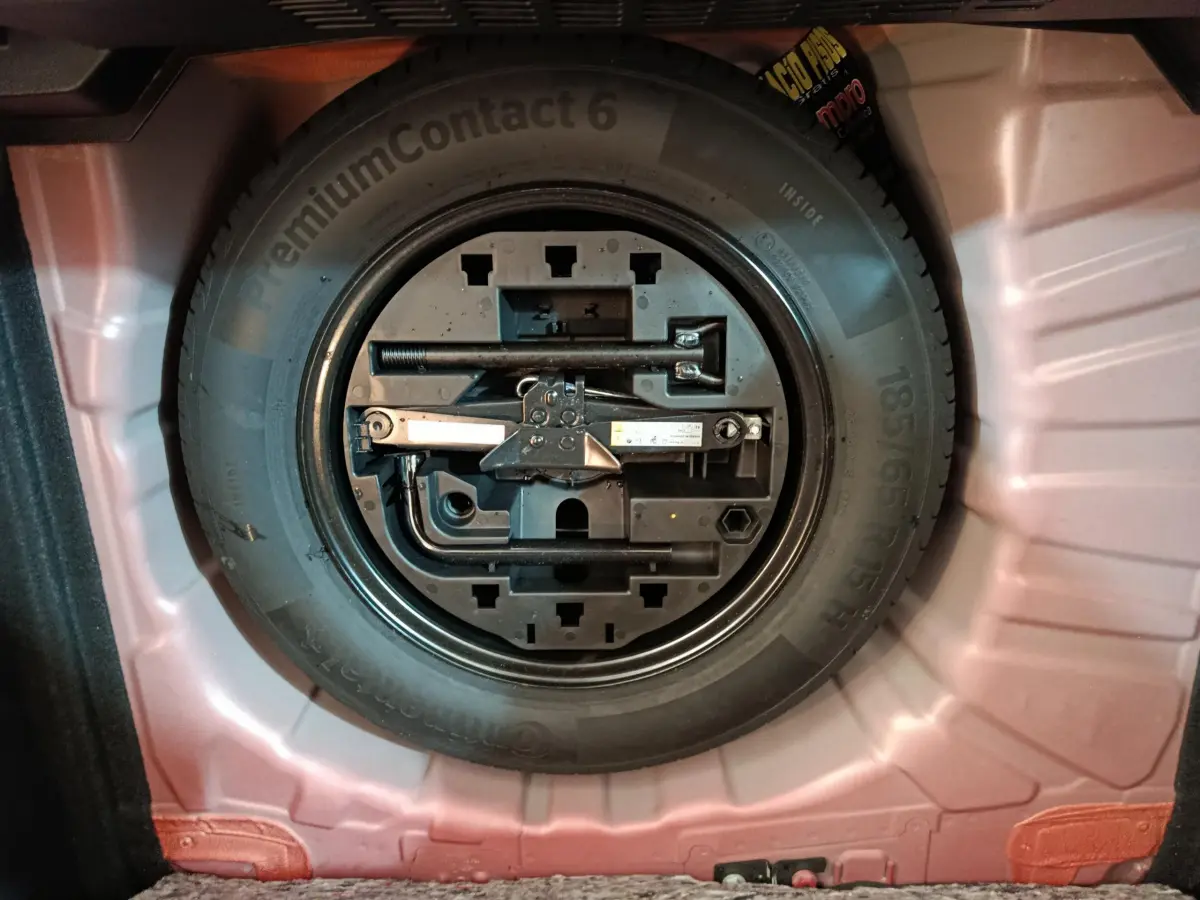 Gros plan sur la roue de secours et les outils de bord dans le coffre rouge d'une Renault Clio Techno TCe 90 2024.