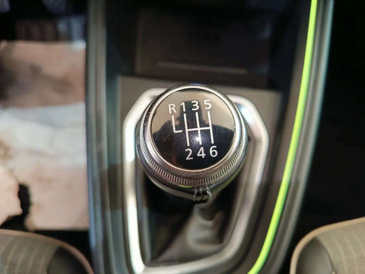 Gros plan sur le levier de vitesses manuel de la Renault Clio Techno TCe 90, entouré d'un éclairage d'ambiance vert pâle.