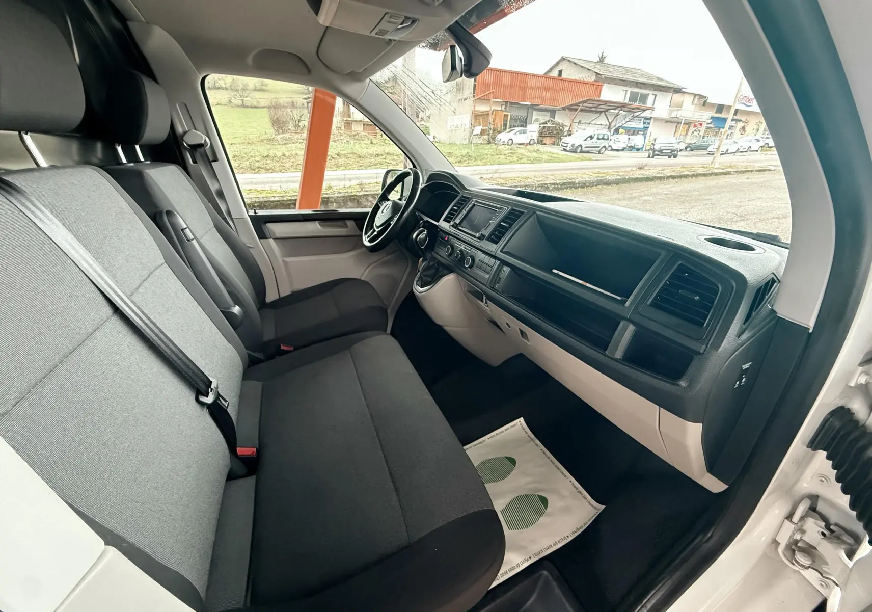 Vue intérieure côté droit du Volkswagen Transporter L1H1 blanc de 2018, montrant les sièges avant et le tableau de bord noir et gris.