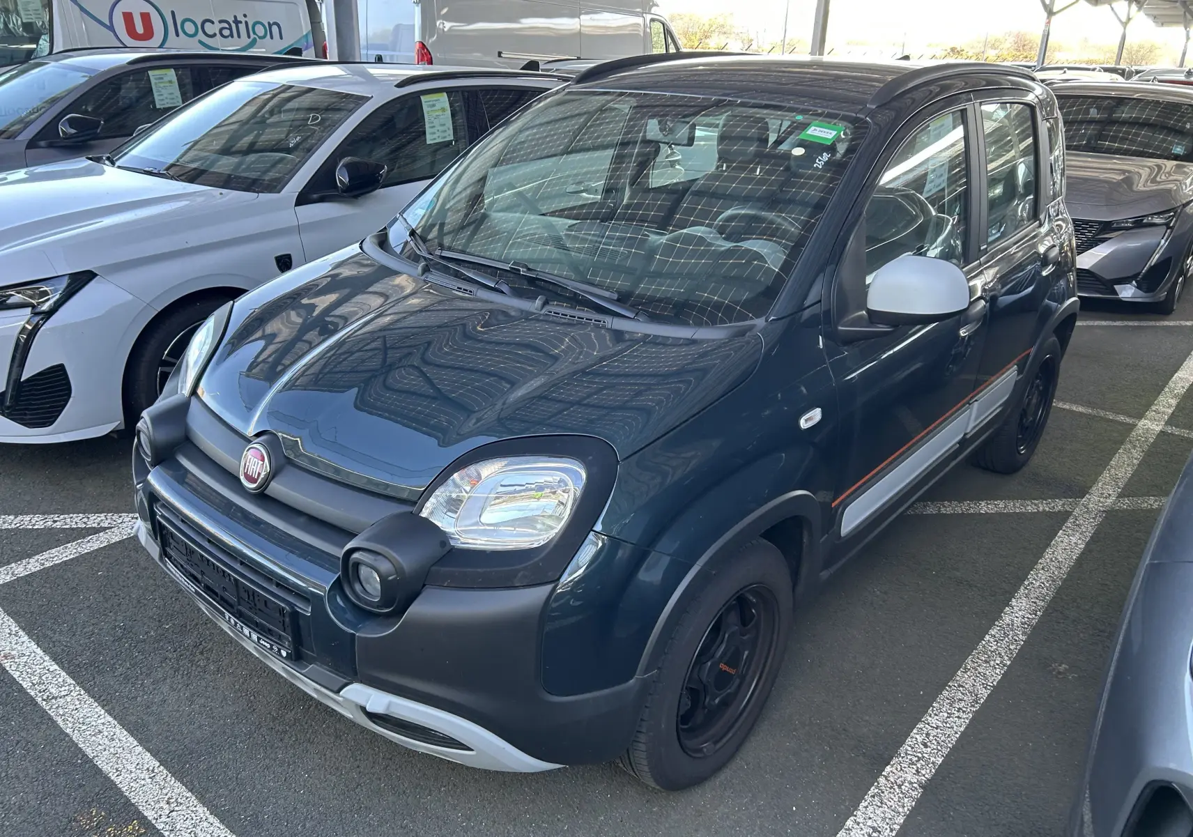 Vue 3/4 avant droite d'une FIAT Panda City Cross 2023 gris minuit avec protections noires et jantes noires.