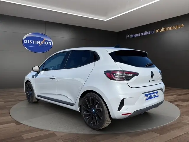 Vue 3/4 arrière droite d'une Renault Clio Esprit Alpine gris clair avec jantes noires et toit noir dans un showroom.