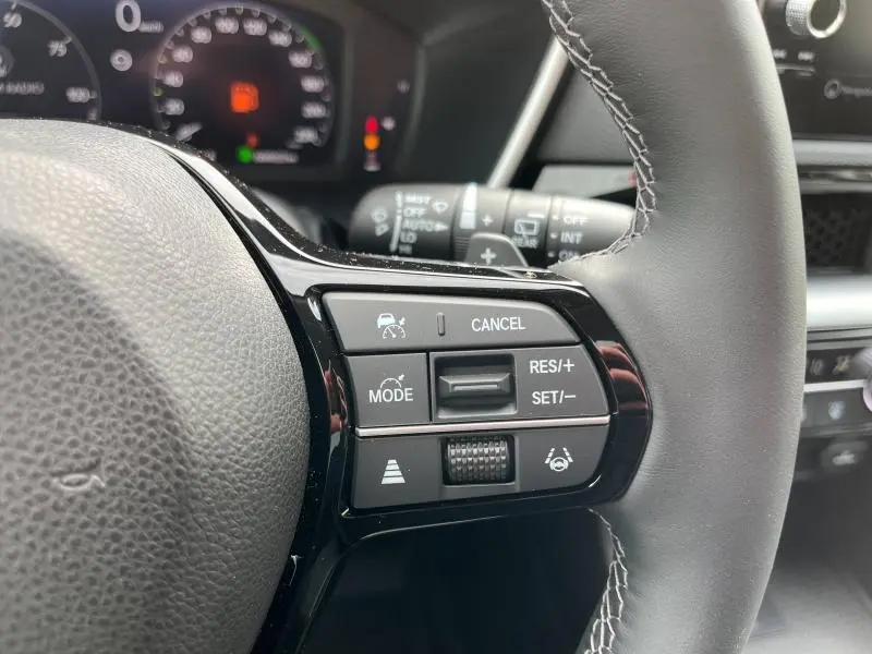 Gros plan sur les commandes du volant côté droit du Honda CR-V blanc nacré 2024 avec régulateur adaptatif et assistant de conduite.