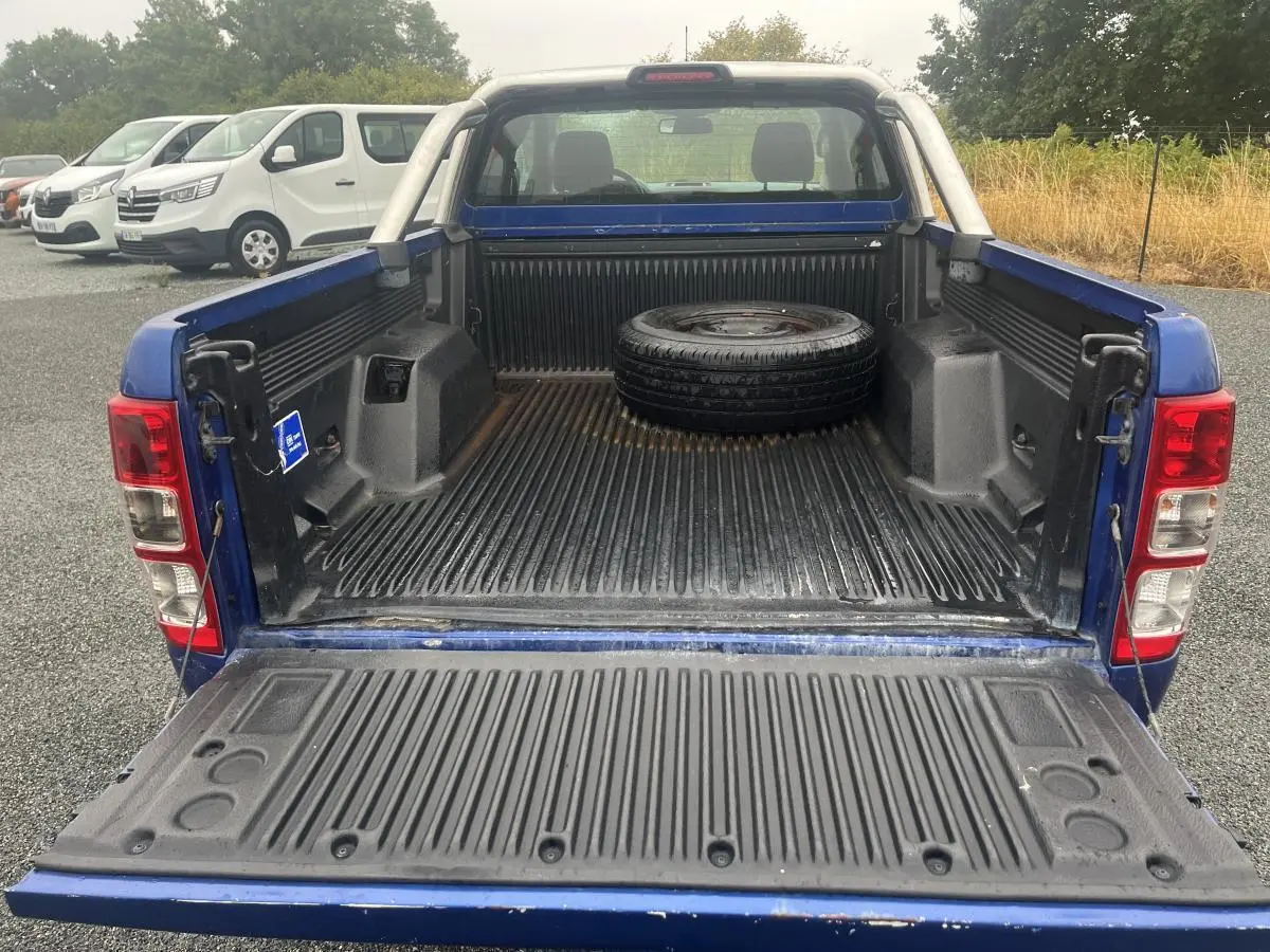 Vue arrière du Ford Ranger bleu 2019 avec benne ouverte et roue de secours posée à l'intérieur.