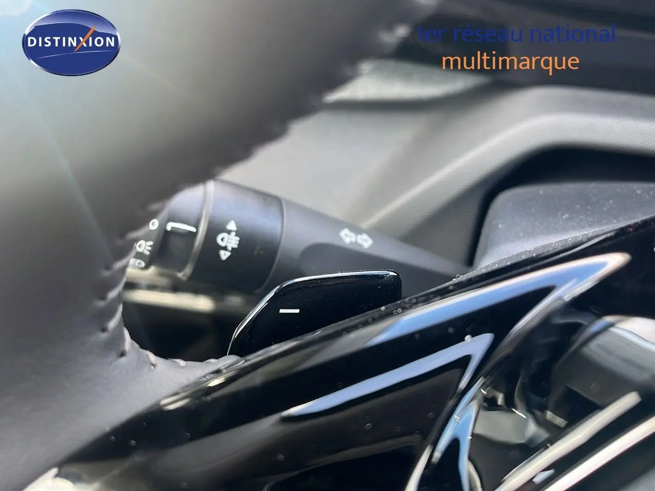 Gros plan sur la palette de changement de vitesse au volant d'une Peugeot 308 hybride, intérieur noir.