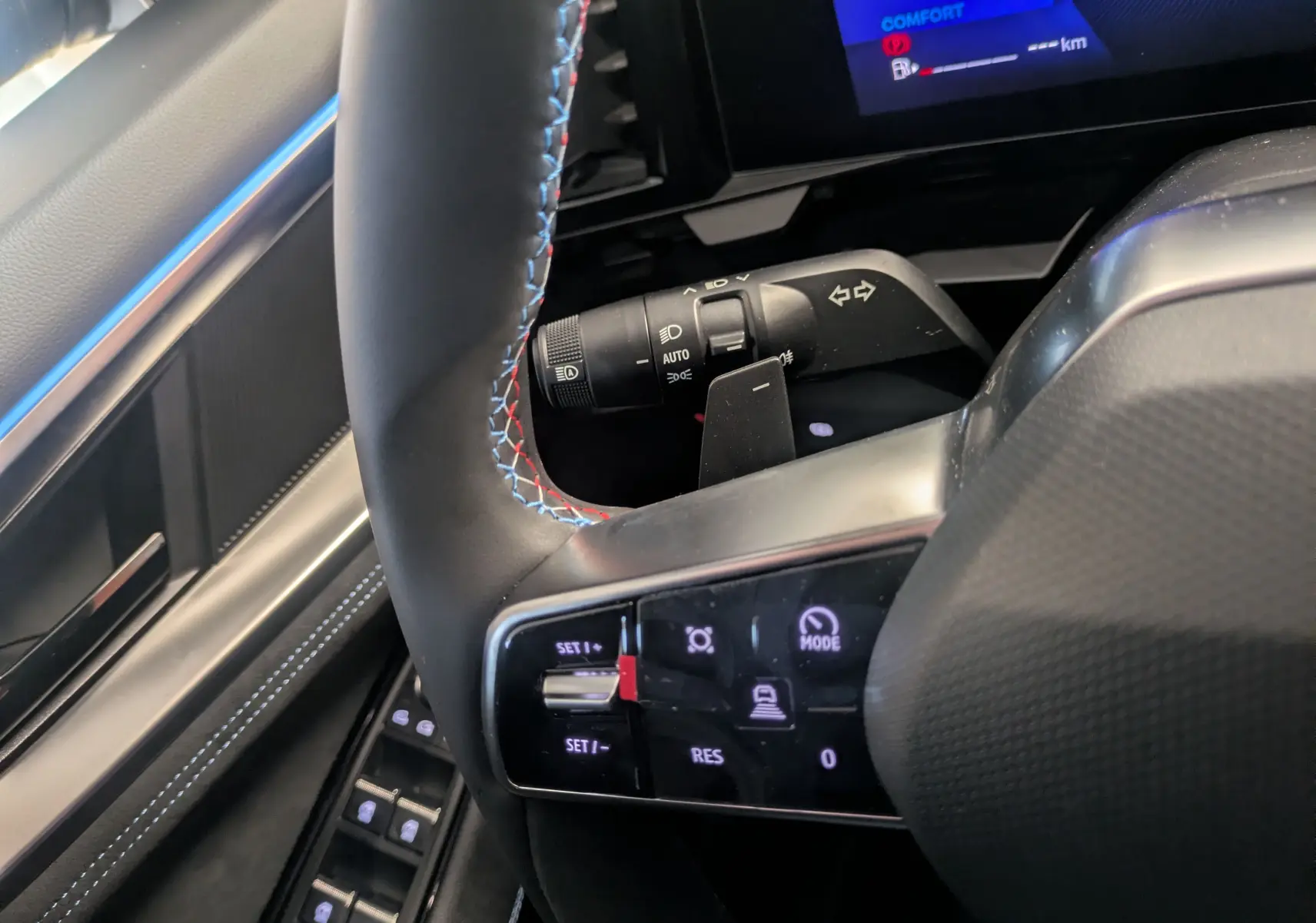 Gros plan sur le volant noir avec surpiqûres tricolores et commandes intégrées du Renault Austral Ph.2 E-TECH 200.