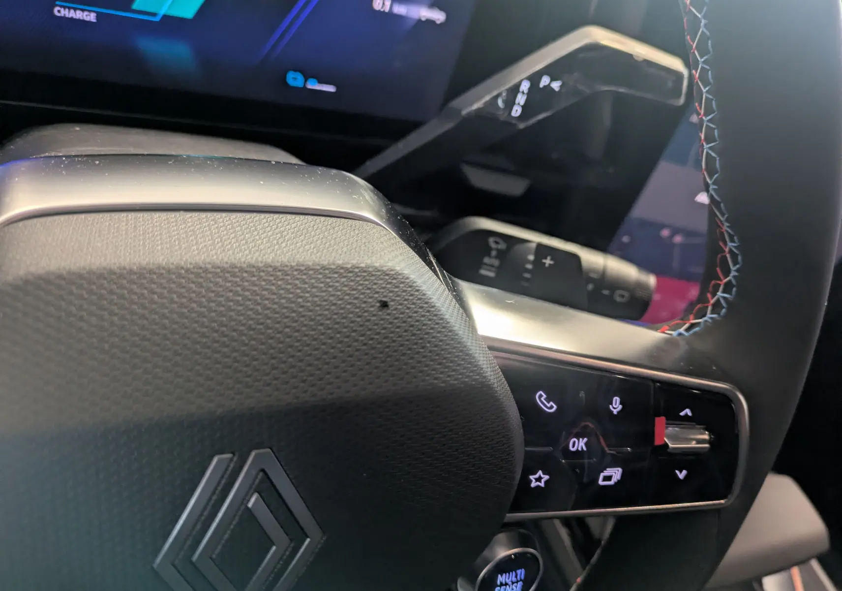 Gros plan sur le volant du Renault Austral Ph.2 E-TECH 200 Esprit Alpine, avec surpiqûres tricolores et commandes intégrées.