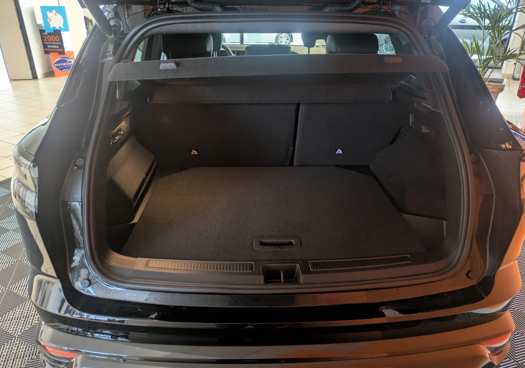 Coffre ouvert vu de l'arrière d'un Renault Austral noir, montrant un espace de chargement spacieux et propre.