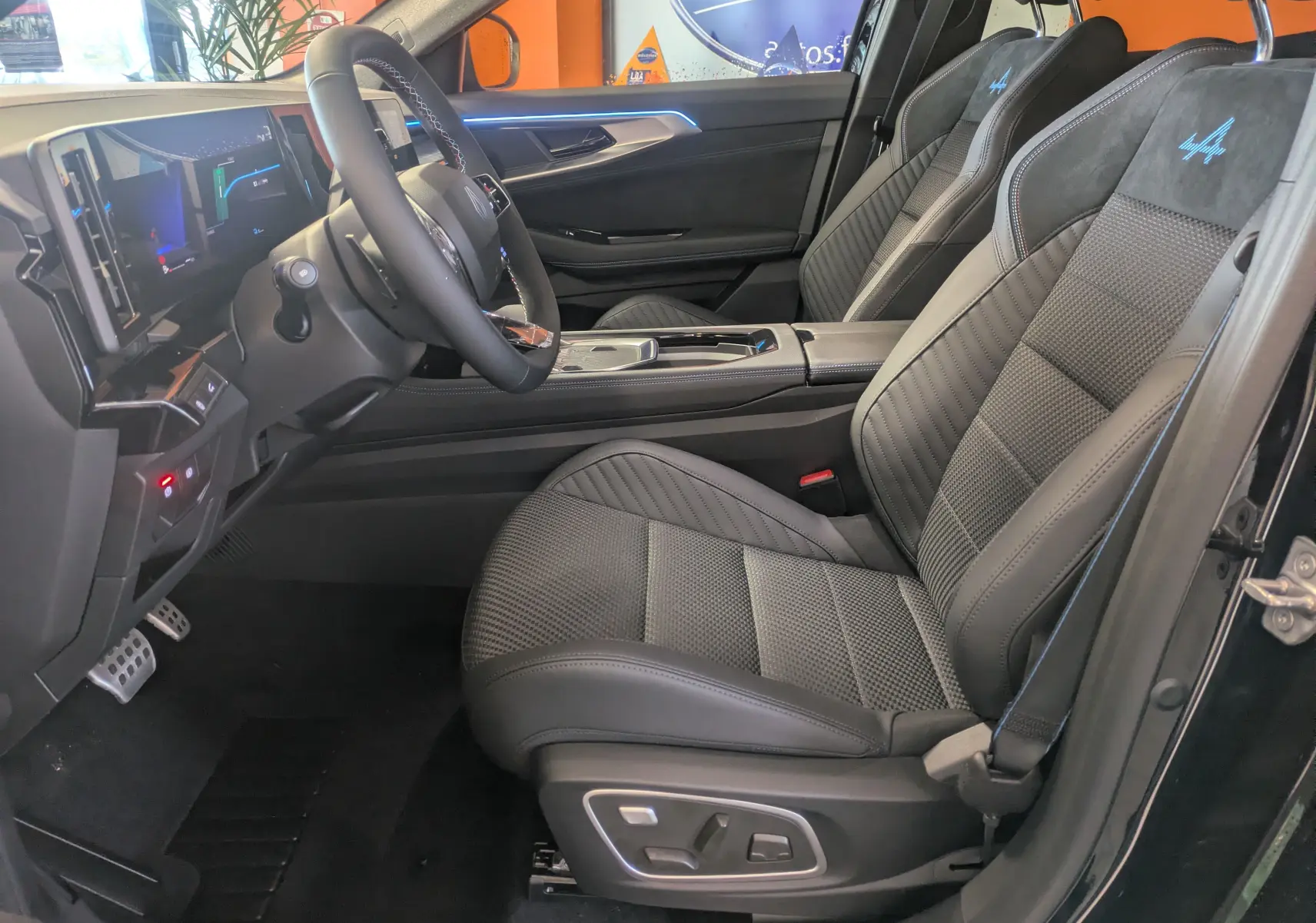Intérieur côté conducteur du Renault Austral noir, sièges sport avec logo Alpine bleu et tableau de bord numérique.