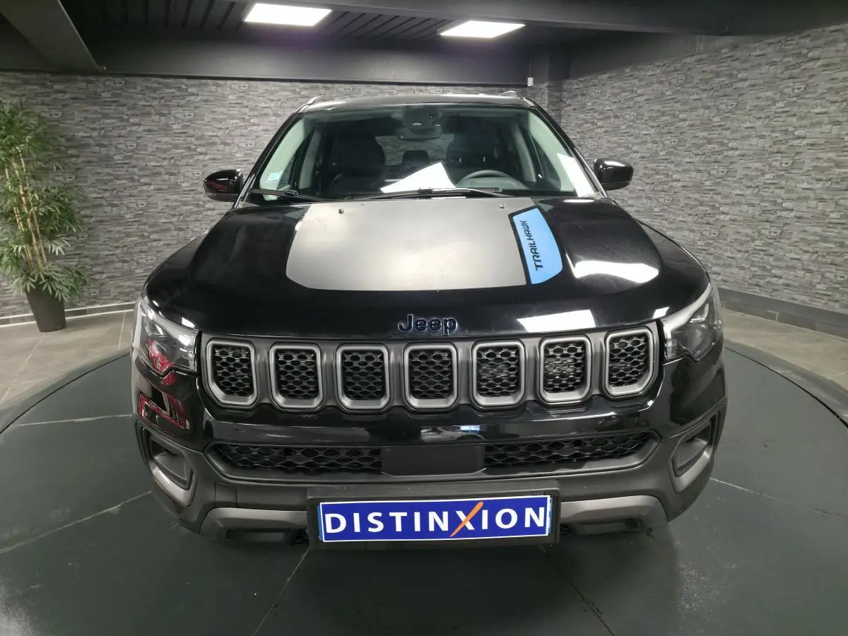 Vue de face d'un Jeep Compass Trailhawk noir avec calandre distinctive et sticker Trailhawk sur le capot.