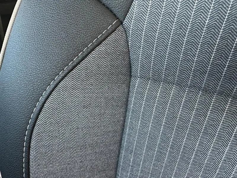 Détail du tissu gris à motif chevrons et cuir noir avec surpiqûres blanches sur un siège Renault Clio 1.6 E-Tech 2025.