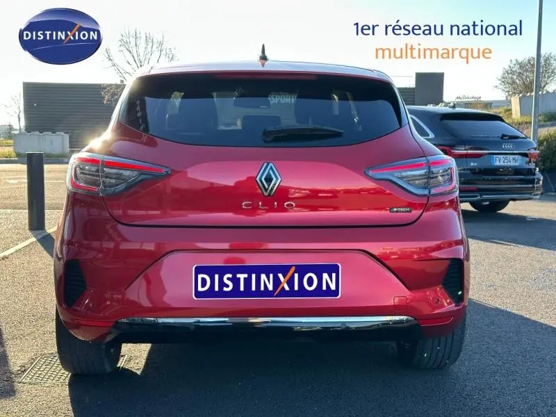Vue arrière d'une Renault Clio 1.6 E-Tech rouge flamme, version hybride, stationnée en extérieur par temps clair.