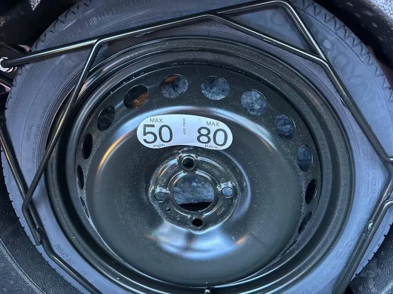 Gros plan sur la roue de secours noire avec étiquette de vitesse, dans le coffre d'une Renault Clio Rouge Flamme 2025.