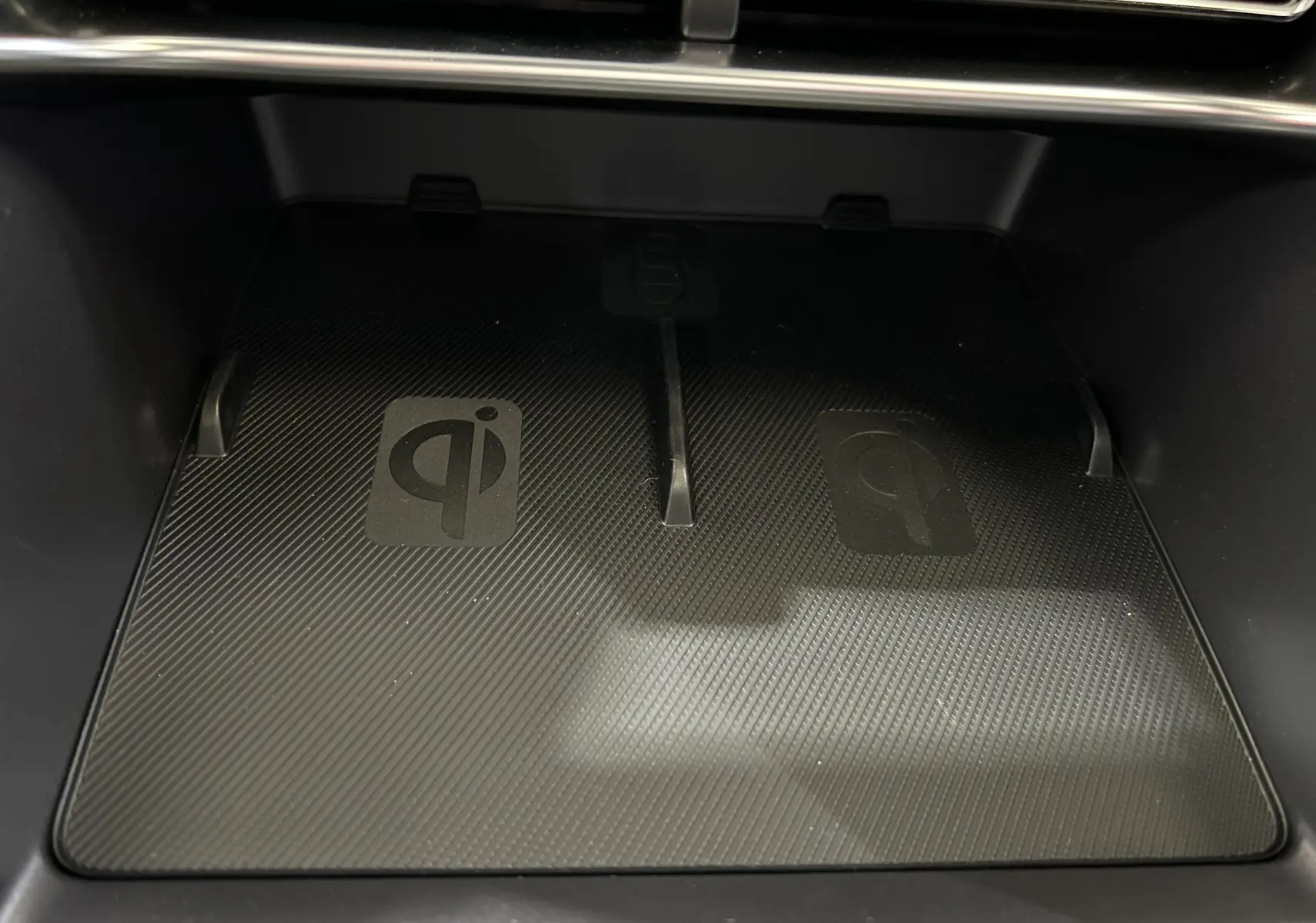 Plateau de recharge sans fil Qi en gros plan dans l'habitacle du BYD SEAL U, surface noire texturée.