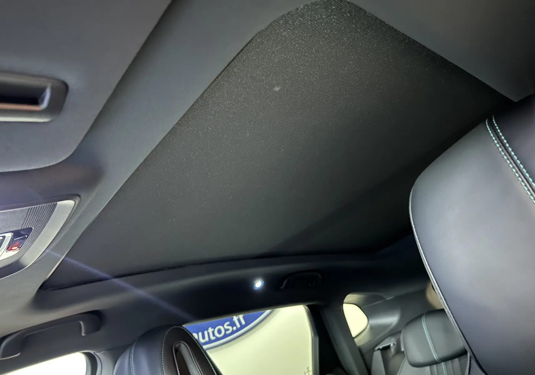 Vue intérieure du toit ouvrant fermé et des sièges en cuir noir avec surpiqûres bleues du BYD SEAL U 2025.