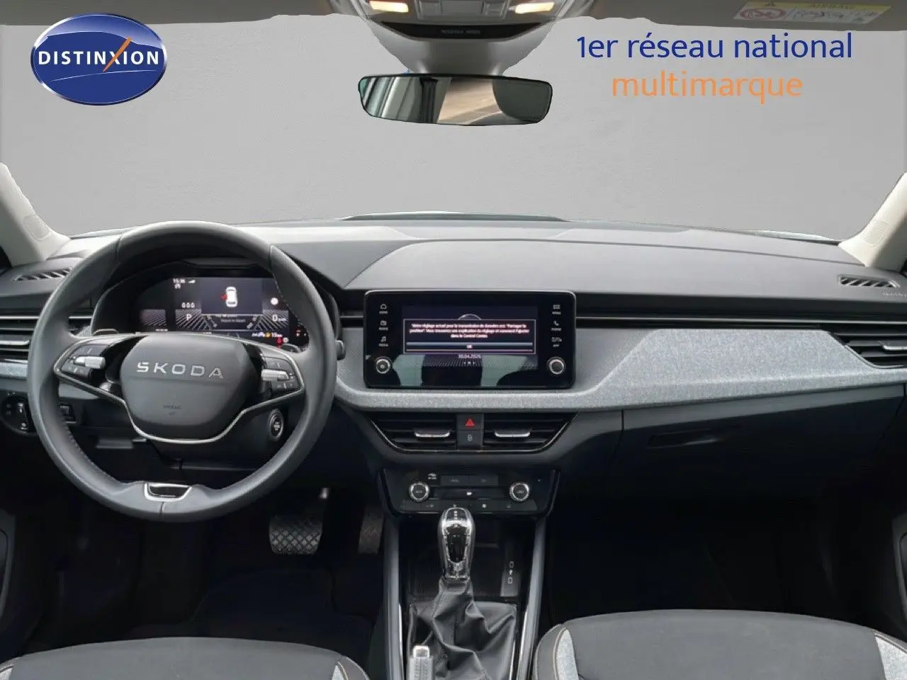 Vue intérieure frontale du tableau de bord et volant SKODA KAMIQ avec écran tactile central et finition tissu noir.