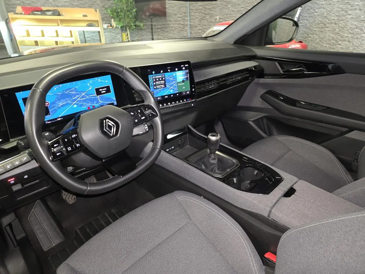 Intérieur avant droit du Renault Austral gris, volant multifonction, écran tactile et boîte manuelle visible.