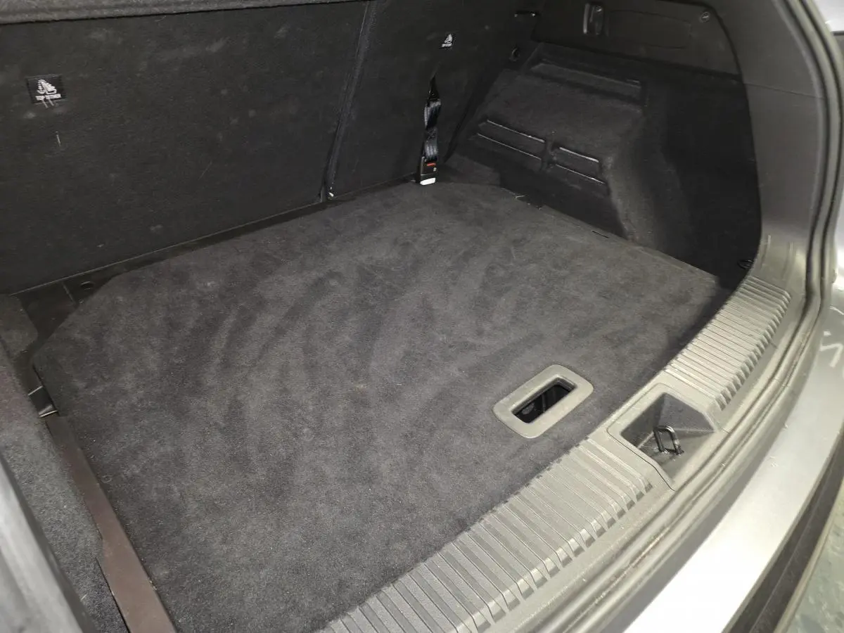 Coffre ouvert du Renault Austral gris, vue plongeante sur le faux plancher en tissu noir.