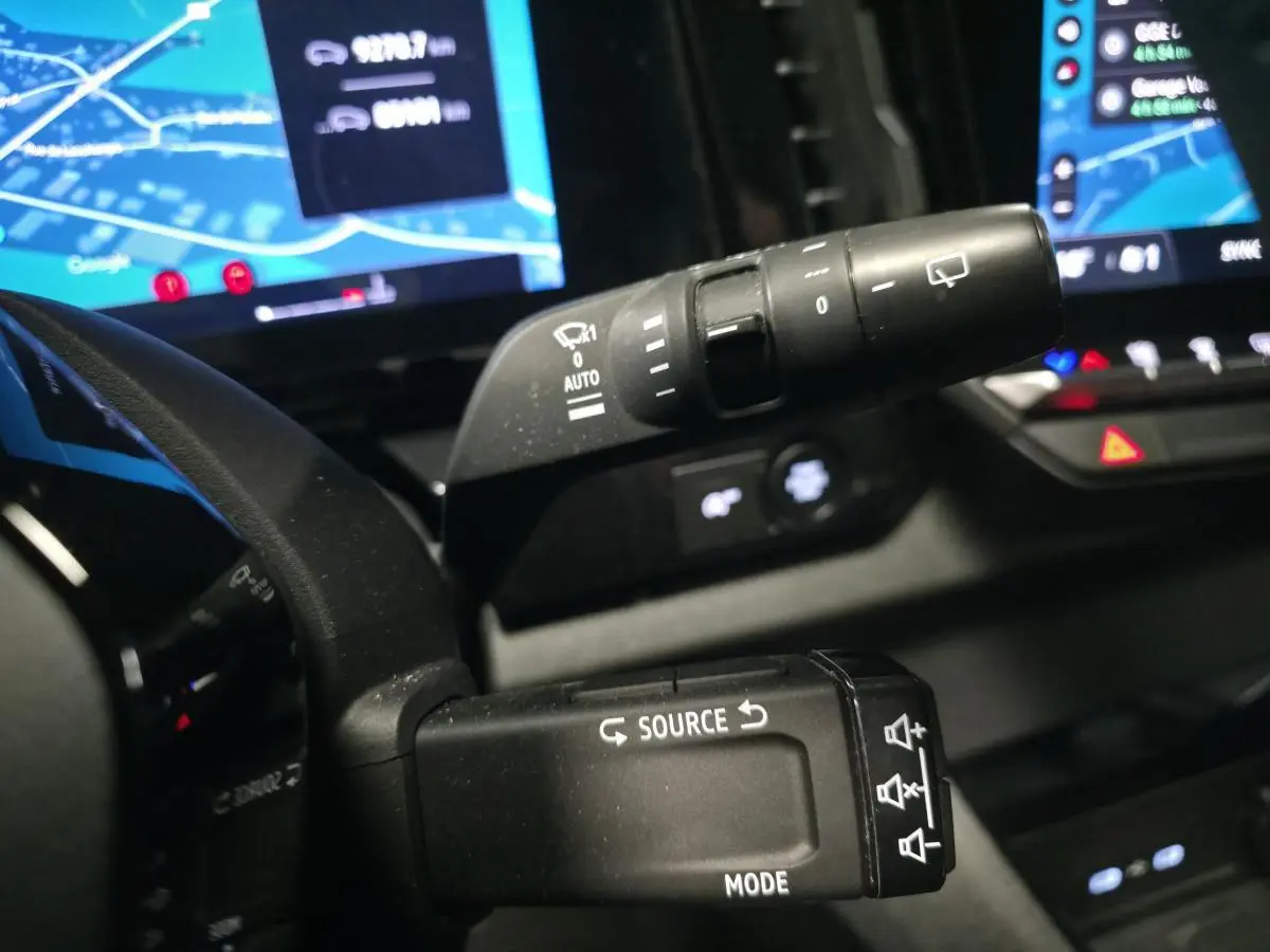 Gros plan sur les commandes au volant du Renault Austral gris, avec tableau de bord digital et écran multimédia en arrière-plan.