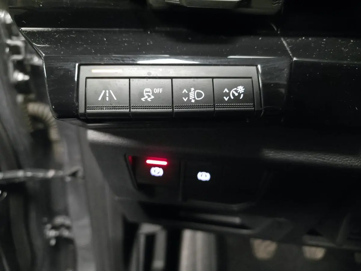 Gros plan sur les commandes noires du tableau de bord du Renault Austral 2024, avec voyants lumineux rouges et blancs.
