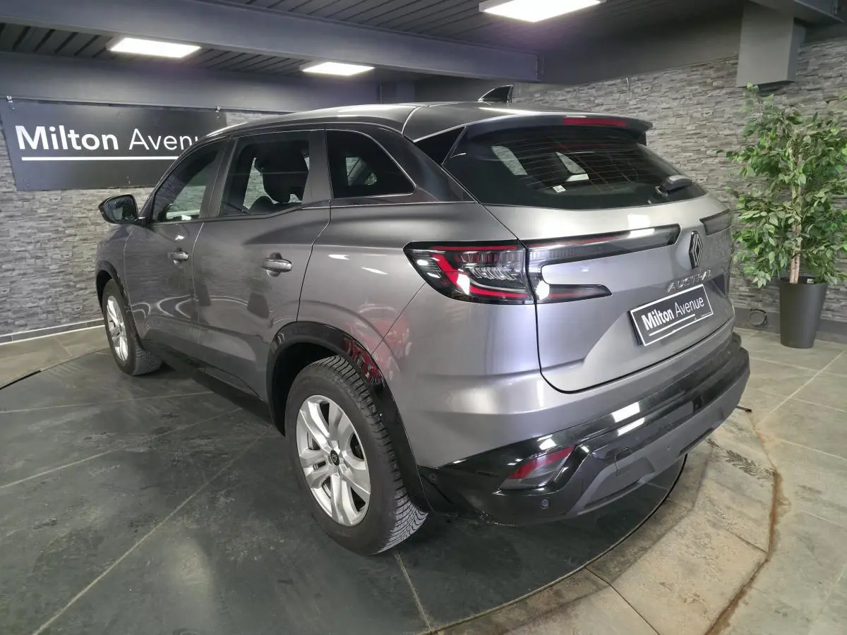 Vue 3/4 arrière droite d'un Renault Austral gris schiste avec feux LED et calandre à damier dans un showroom.