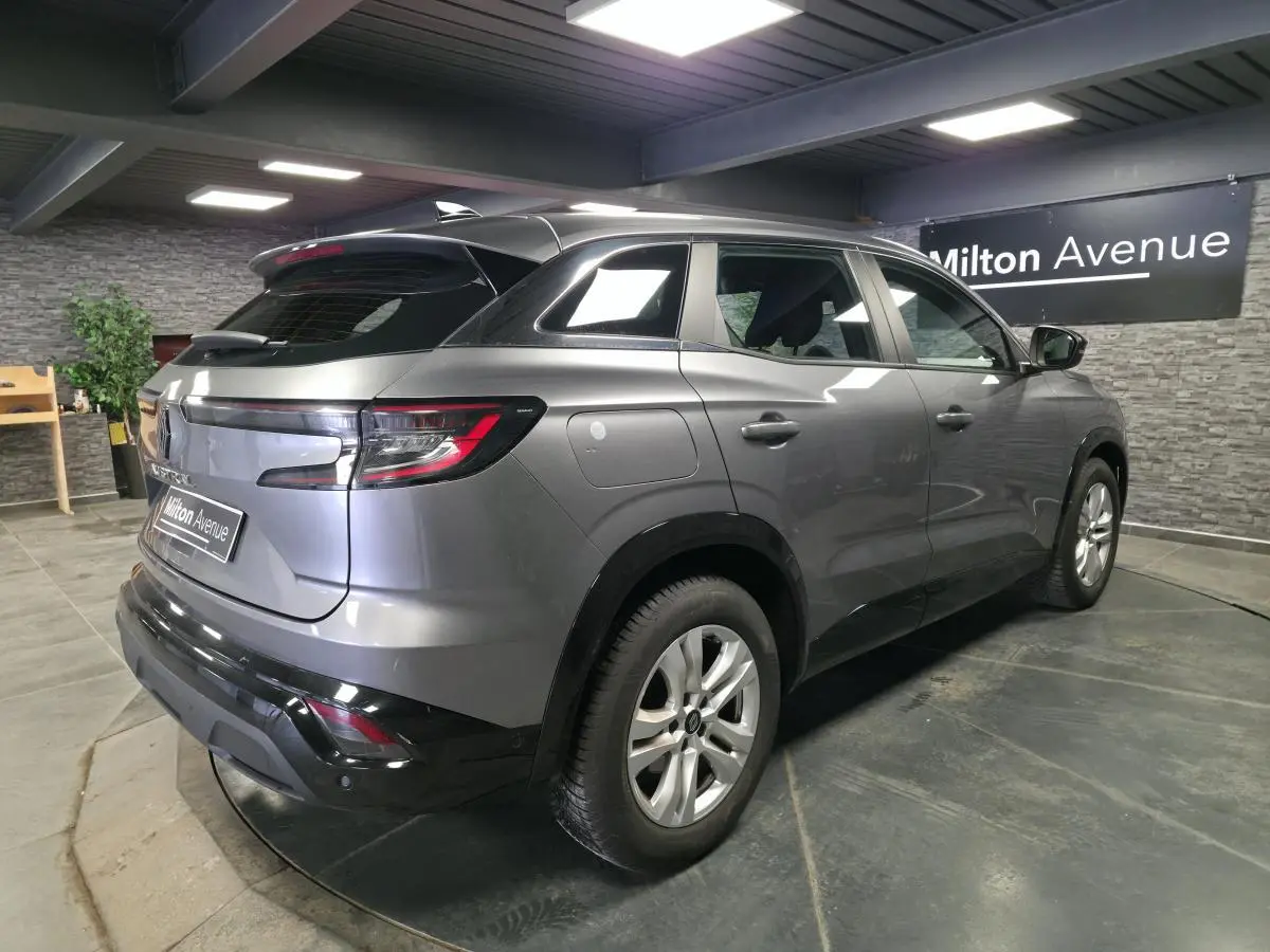 Vue 3/4 arrière droite du Renault Austral gris schiste avec feux LED et jantes alliage en intérieur showroom.