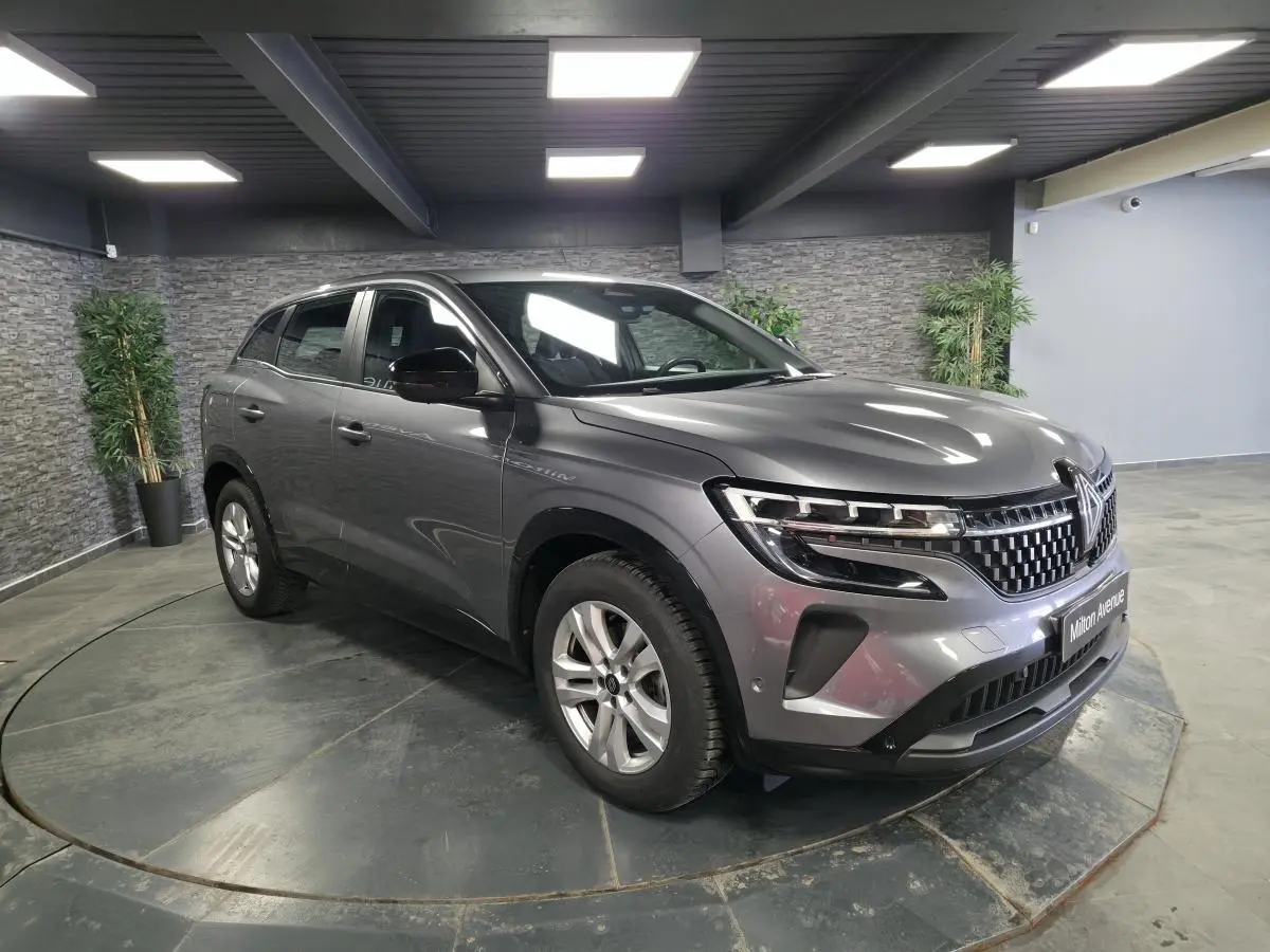 Renault Austral gris schiste en 3/4 avant droit, calandre damier ice black et feux LED Pure Vision visibles.