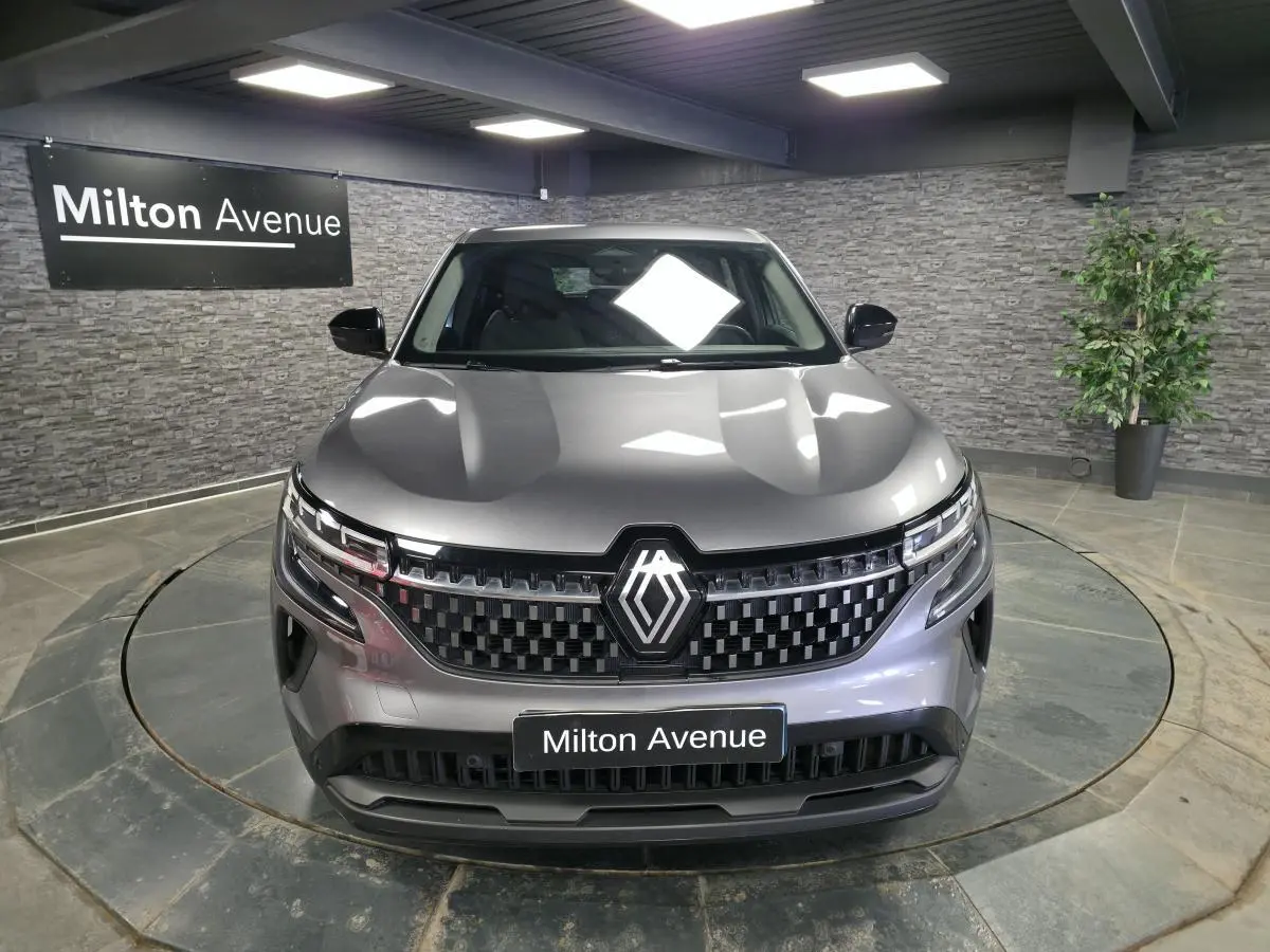 Renault Austral gris vu de face en intérieur, avec calandre damier ice black et logo central lumineux.