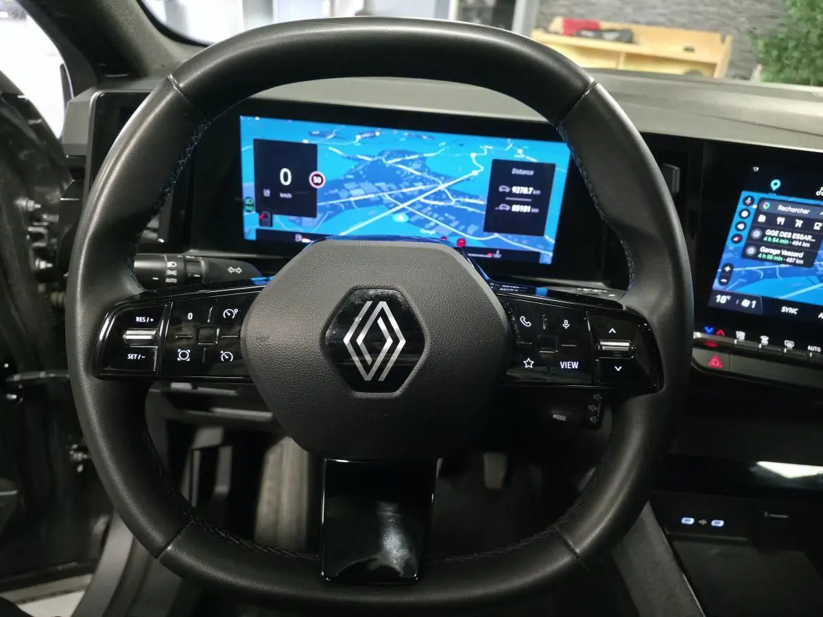 Vue rapprochée du volant noir de la Renault Austral 2024 avec écran numérique et tableau de bord tactile lumineux.
