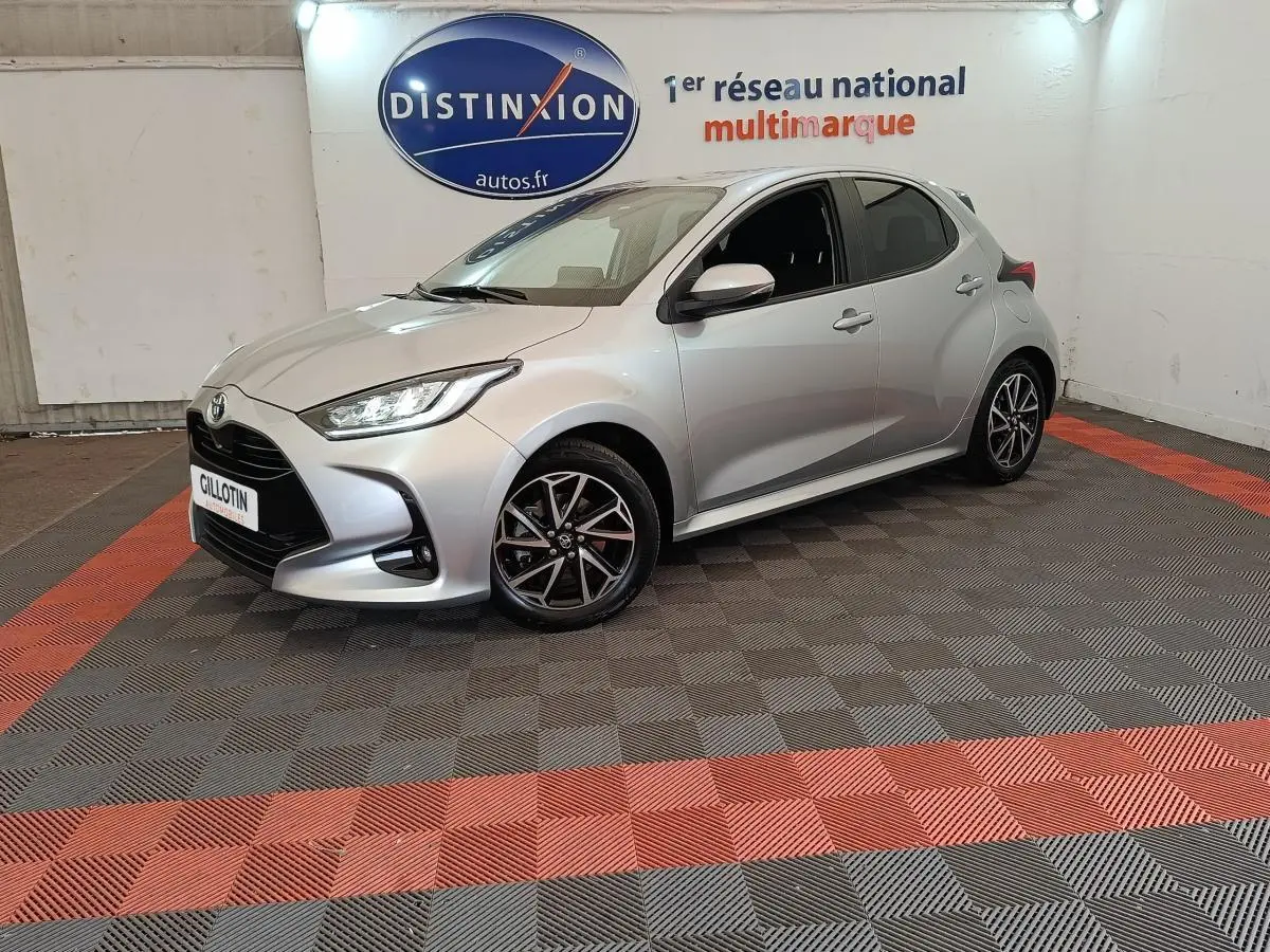 Toyota Yaris Hybride 116h gris clair vue 3/4 avant droit avec jantes alliage et phares LED ellipsoïdaux.