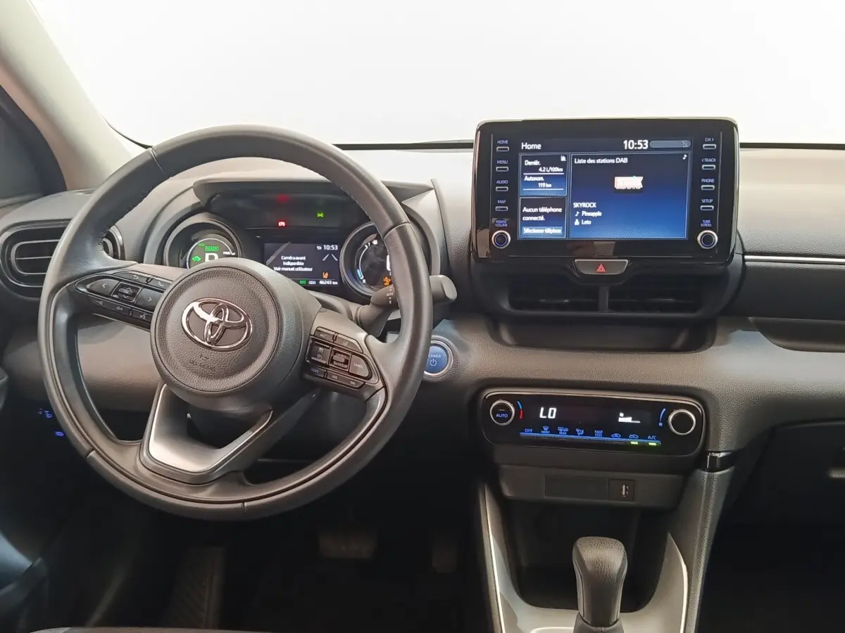 Vue intérieure centrée sur le volant cuir et l'écran tactile 8 pouces du tableau de bord de la Toyota Yaris hybride 2023.