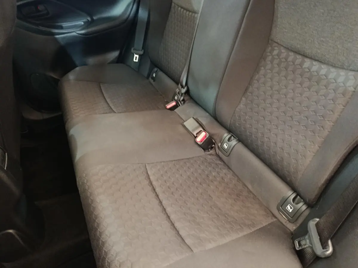 Vue latérale intérieure des sièges arrière gris foncé de la Toyota Yaris Hybride 116h Design 2023, avec ceintures de sécurité visibles.