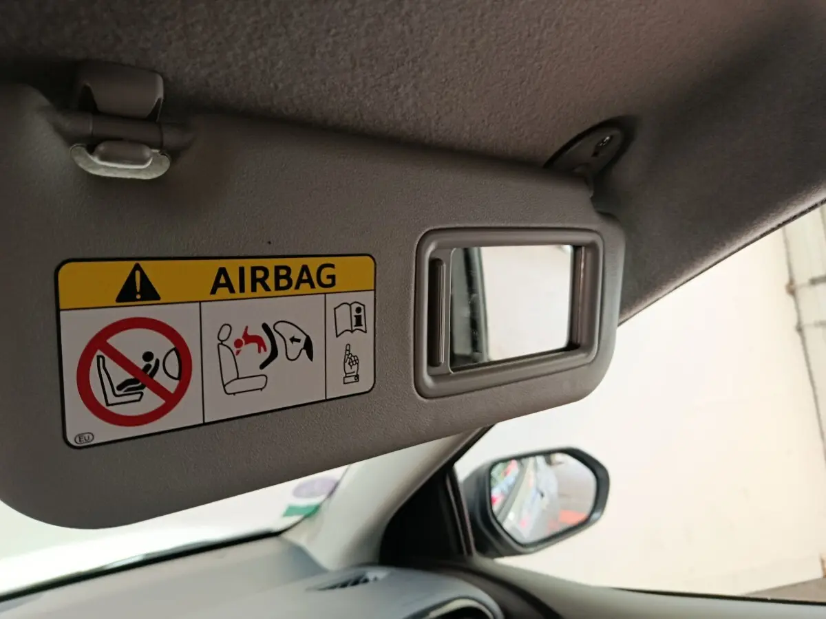 Détail du pare-soleil côté conducteur avec miroir de courtoisie et avertissement airbag dans une Toyota Yaris gris clair.