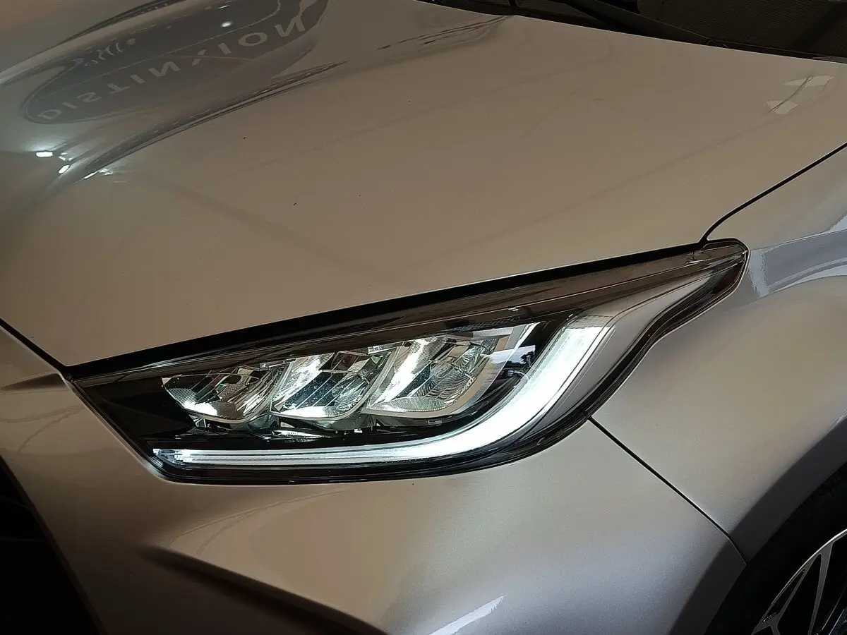 Gros plan sur le phare avant droit d'une Toyota Yaris hybride gris clair 2023, soulignant son design LED moderne.