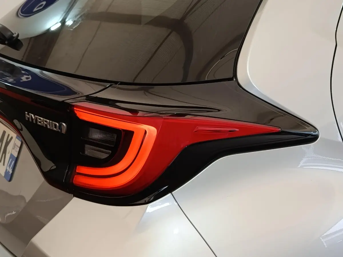 Gros plan sur le feu arrière droit rouge et noir de la Toyota Yaris hybride gris clair 2023, avec logo Hybrid visible.