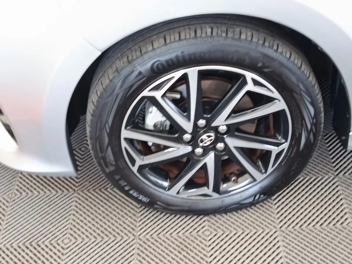 Gros plan sur la roue avant droite de la Toyota Yaris hybride gris clair, avec jante alliage noire et argentée.