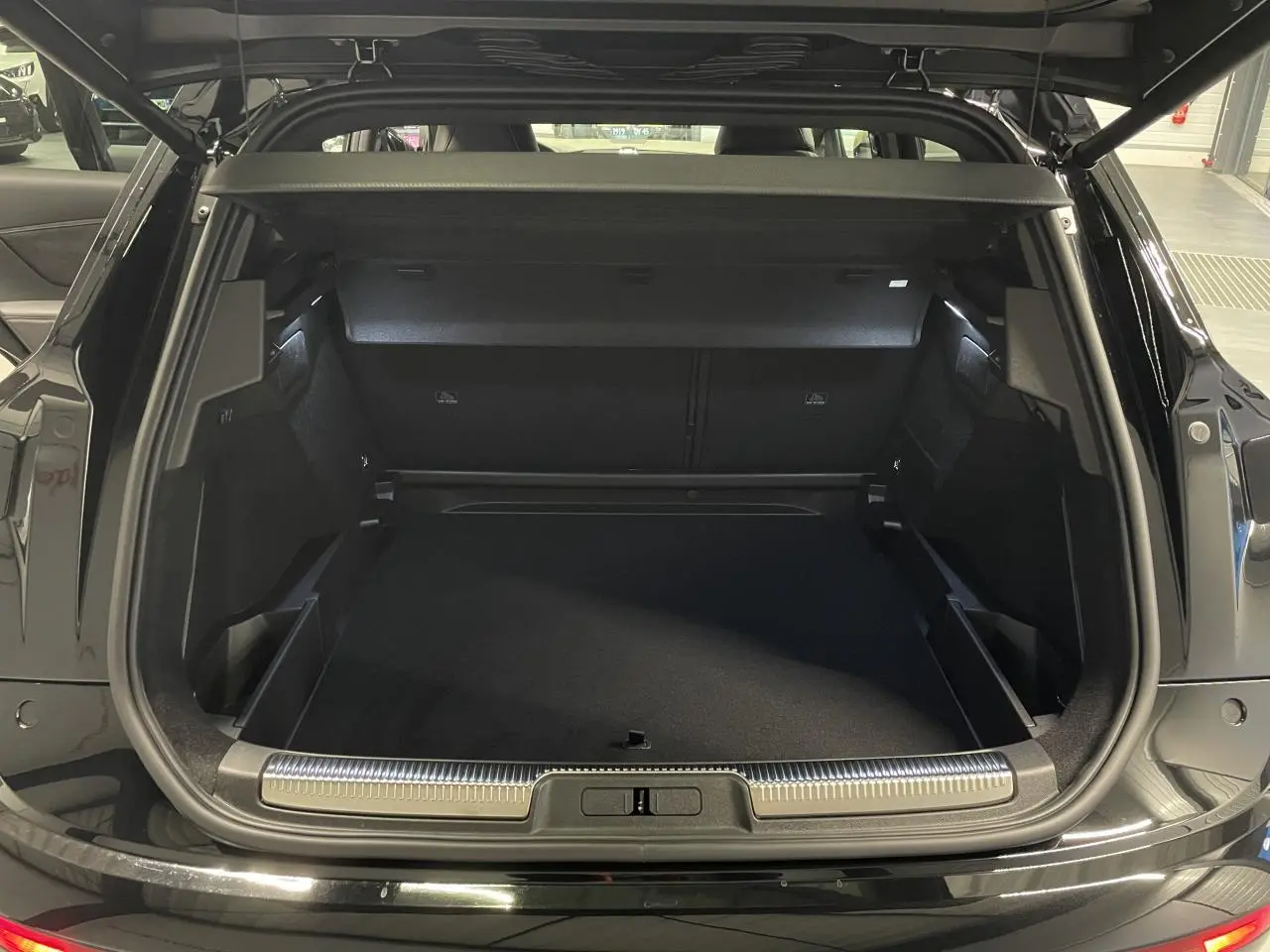 Coffre ouvert du DS7 Crossback noir métallisé, vue arrière montrant l’espace de chargement et le seuil chromé.