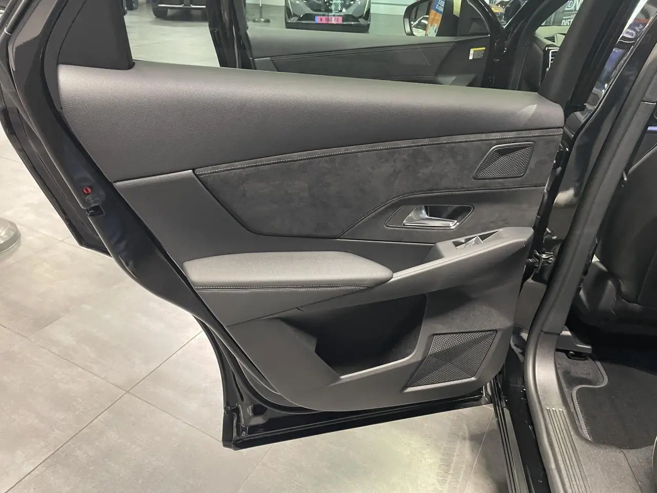 Porte arrière gauche ouverte d'un DS7 Crossback noir métallisé, avec garniture intérieure en Alcantara noir et surpiqûres contrastées.