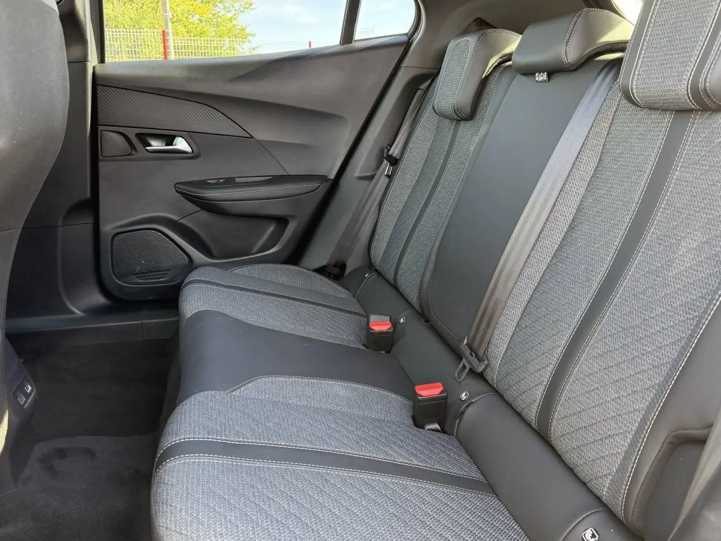 Vue latérale droite de la banquette arrière gris tissu et cuir du Peugeot e-2008 2025 avec ceintures et appuie-têtes.