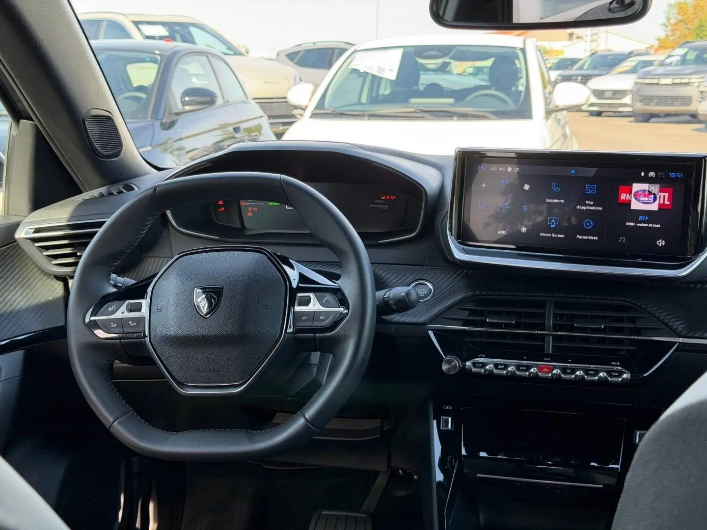 Intérieur de la Peugeot e-2008 2025 vu de face, volant multifonction et écran tactile central allumé.