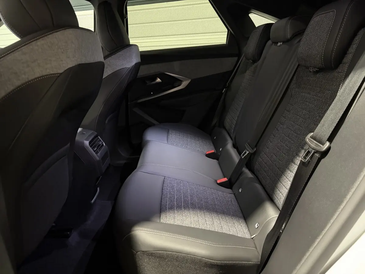 Vue intérieure arrière droite des sièges arrière en tissu et cuir gris du Peugeot 3008 blanc hybride 2026.