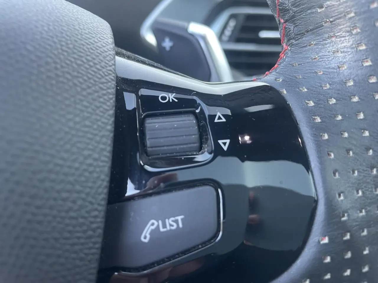Gros plan sur les commandes au volant en cuir perforé avec surpiqûres rouges de la Peugeot 308 SW GT Pack 2021.