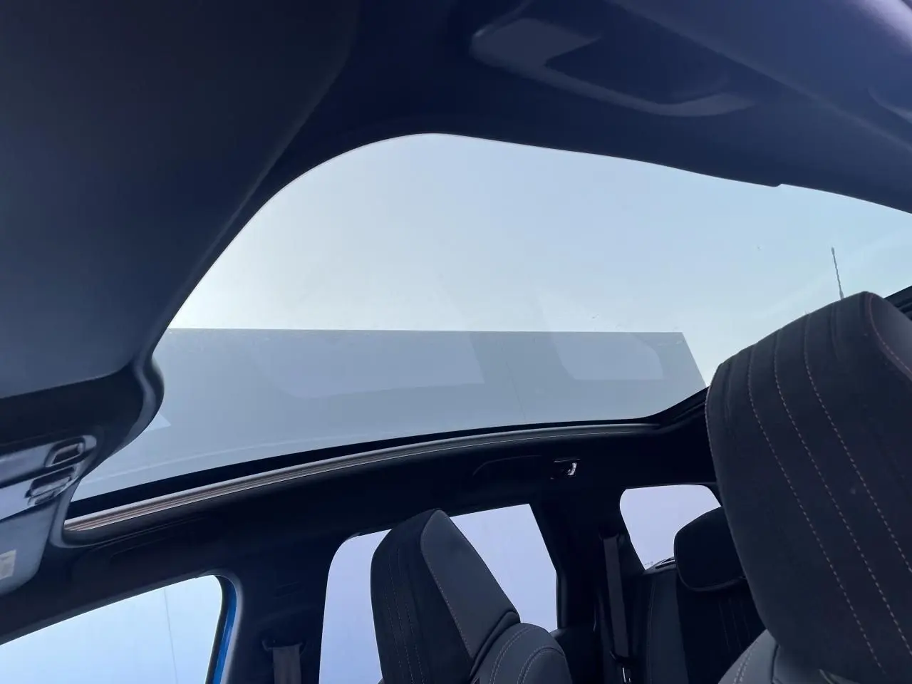 Toit panoramique en verre avec occulteur électrique sur Peugeot 308 SW 2021 bleu Vertigo, vue intérieure arrière côté droit.