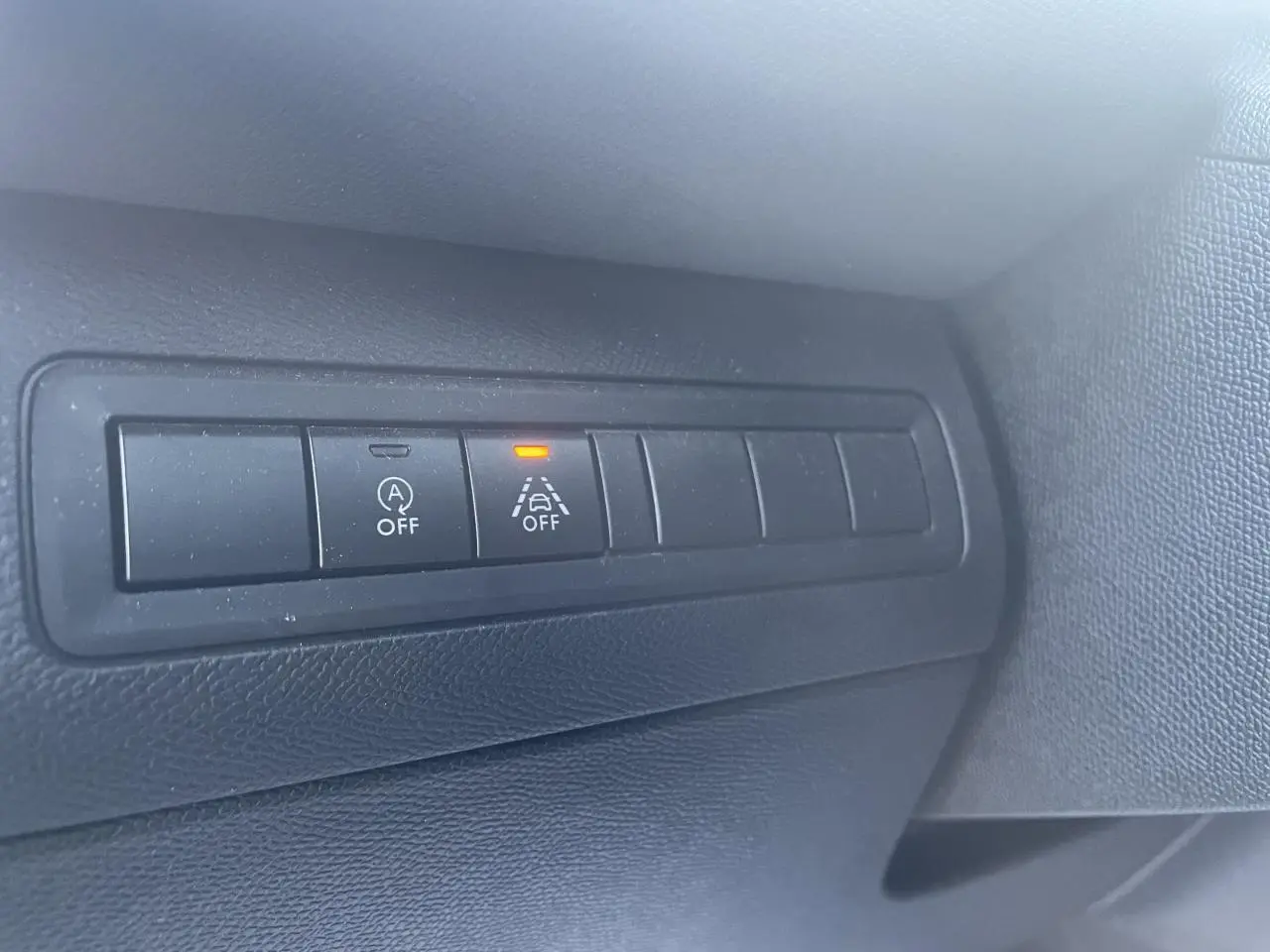 Gros plan sur les boutons de commande noirs du tableau de bord intérieur d'une Peugeot 308 SW bleu Vertigo.