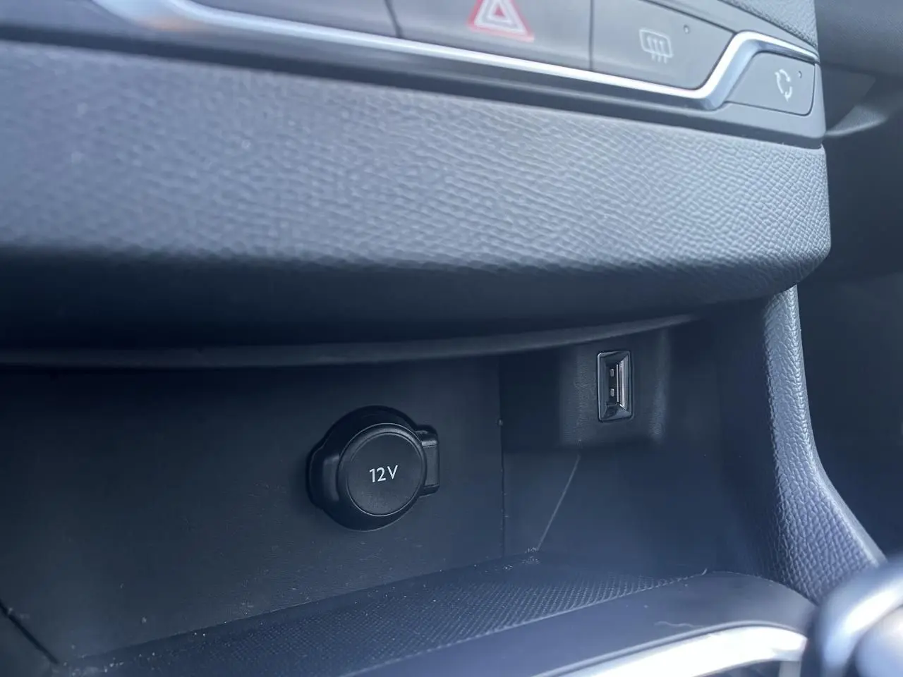Prise 12V et port USB dans la console centrale noire de la Peugeot 308 II SW Bleu Vertigo, vue intérieure rapprochée.