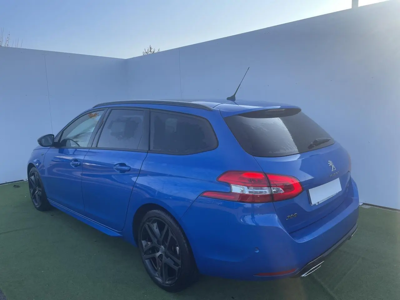 Peugeot 308 SW bleu Vertigo vue 3/4 arrière droit avec jantes alliage noires et toit panoramique.