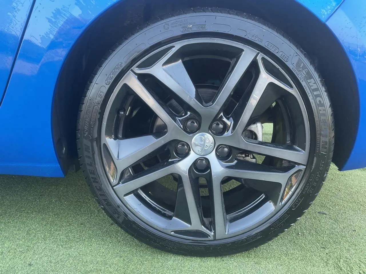 Gros plan sur la jante alliage 18 pouces diamantée noire et grise du côté gauche d'une Peugeot 308 SW bleu Vertigo.